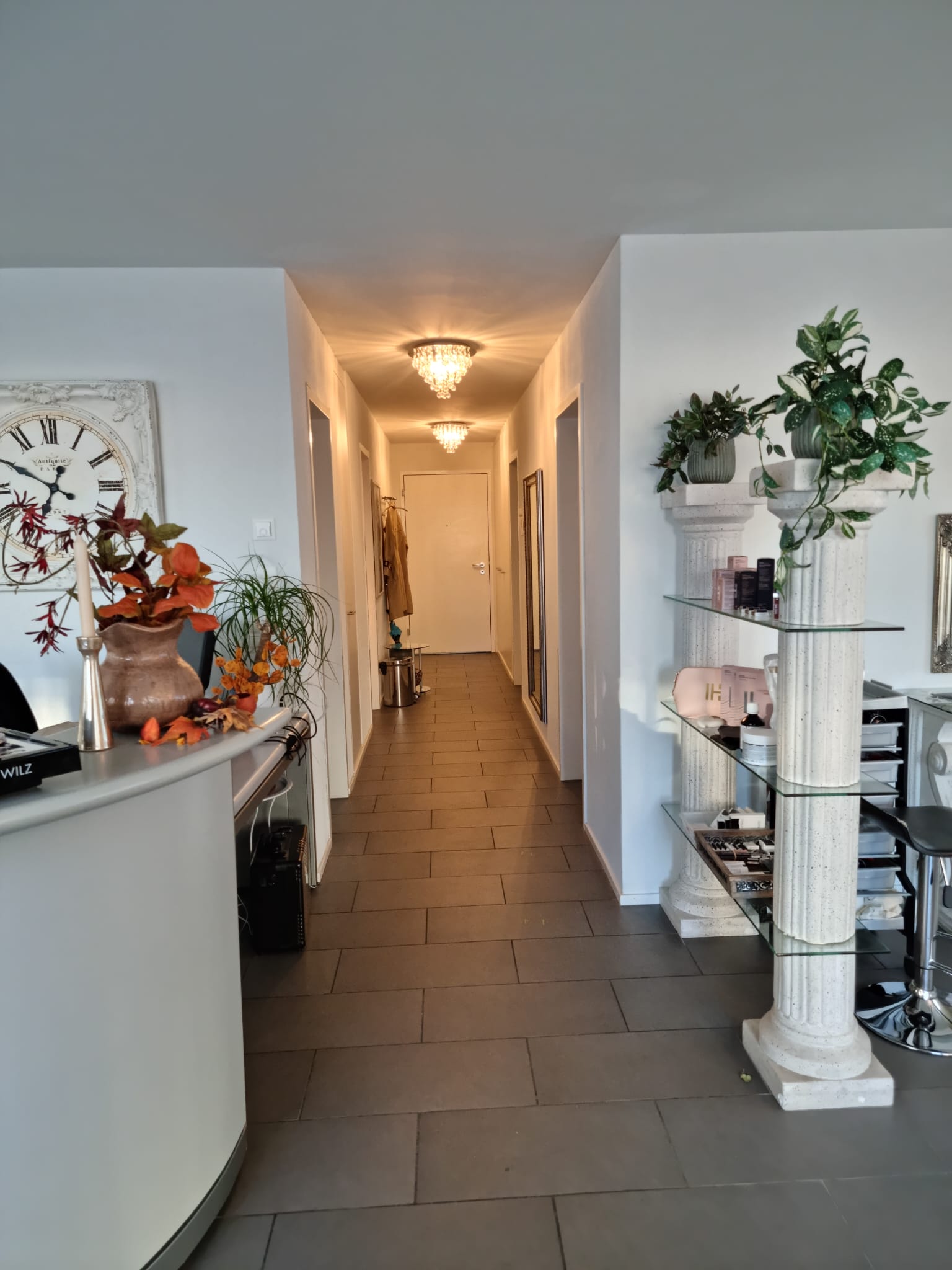 Ein langer Flur führt zu einem Rezeptionstresen in einem Zimmer.