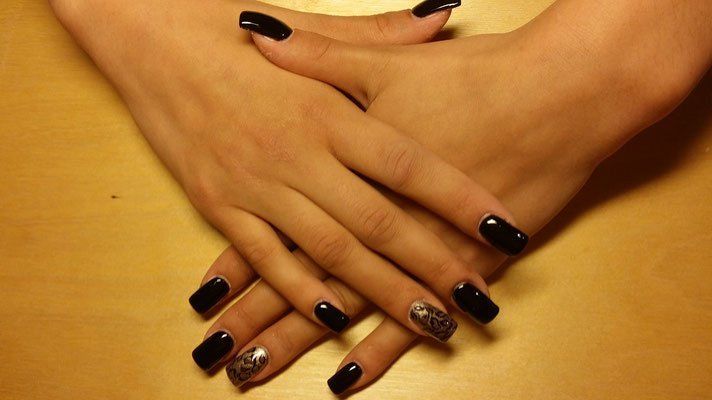 Eine Nahaufnahme der Hände einer Frau mit schwarzen Nägeln