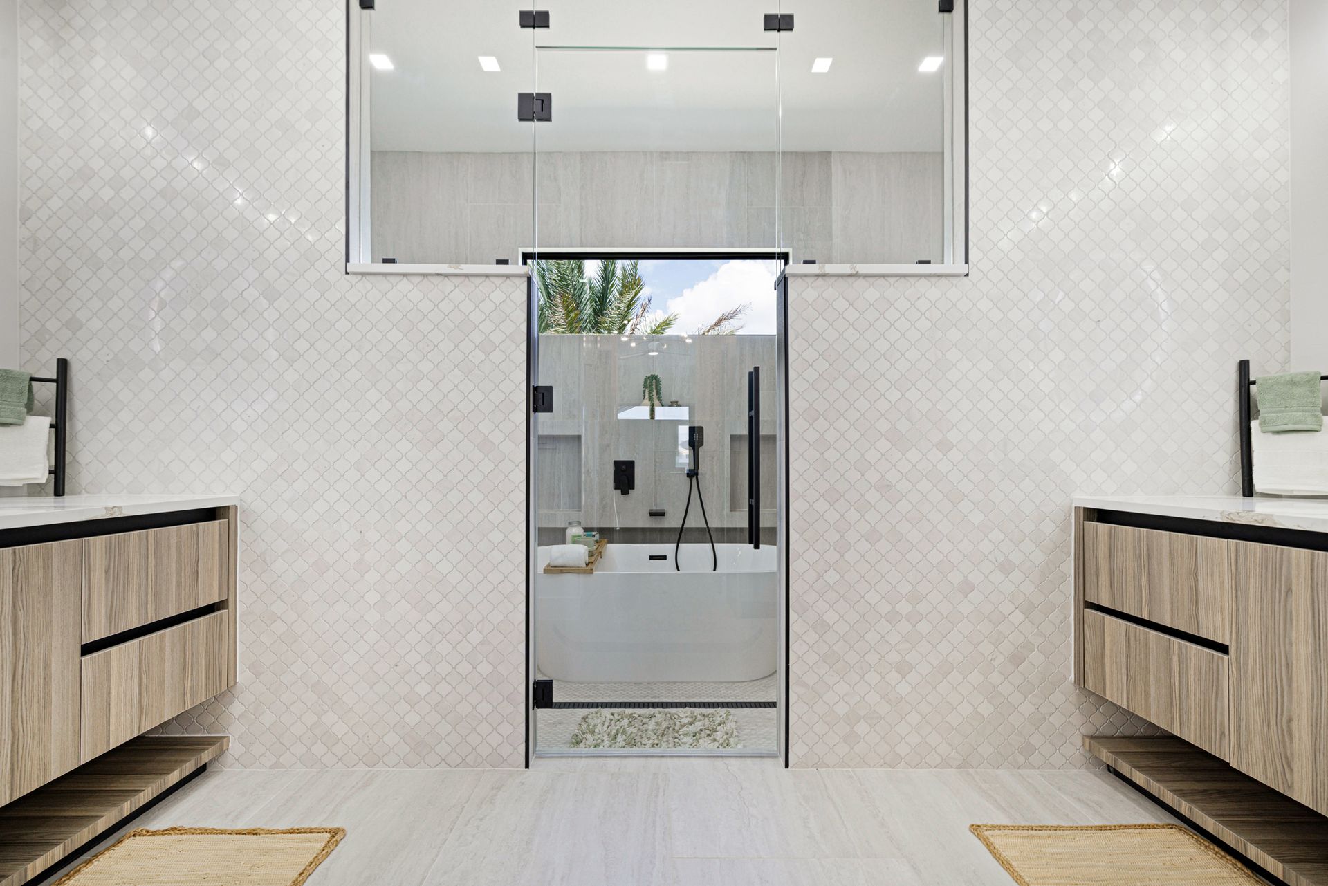 A modern bathroom with a glass shower and dual sinks, white walls, and wood-toned cabinets.