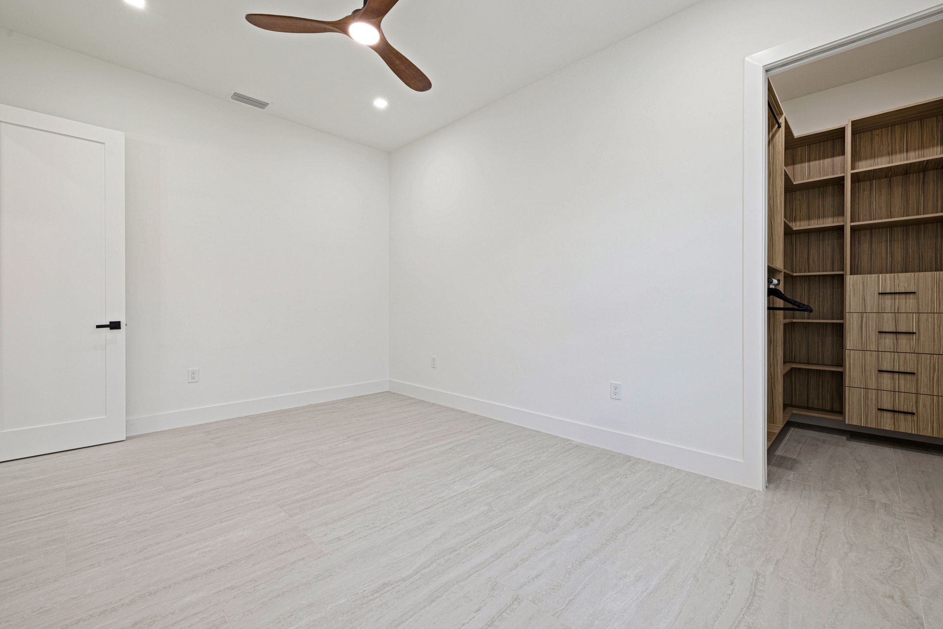 Empty bedroom with white walls, wood floor, and closet.