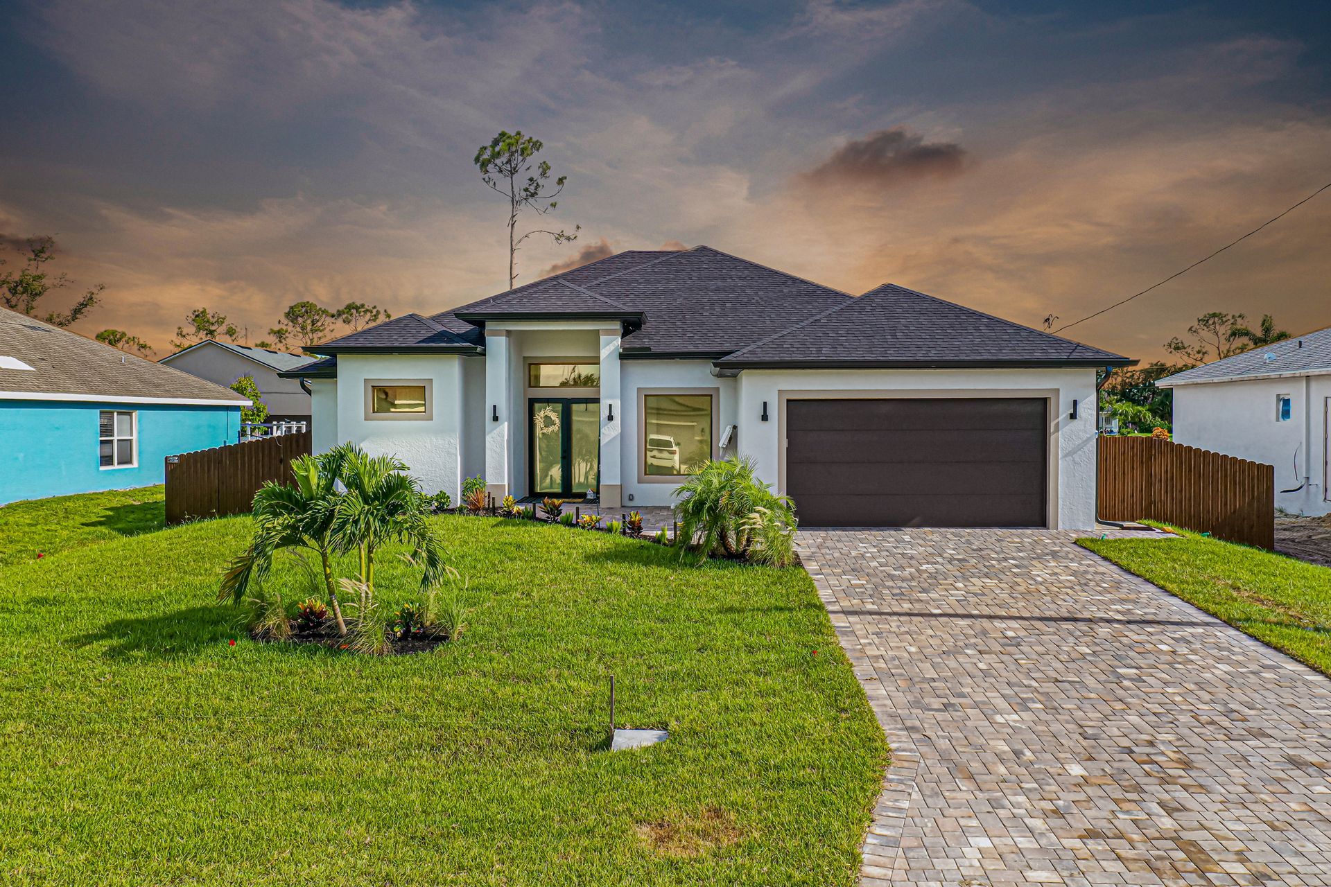 Modern single-story house with pale blue siding, brown garage door, and a paved driveway.