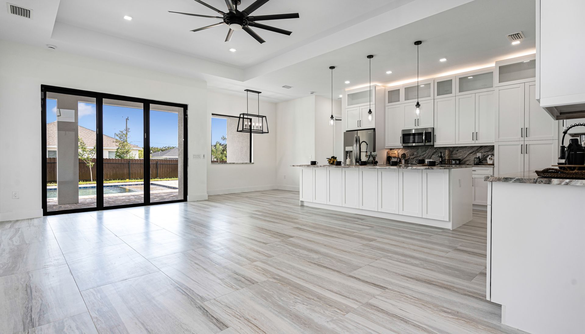 Bright, modern kitchen with white cabinets, island, and folding glass doors to a backyard pool.