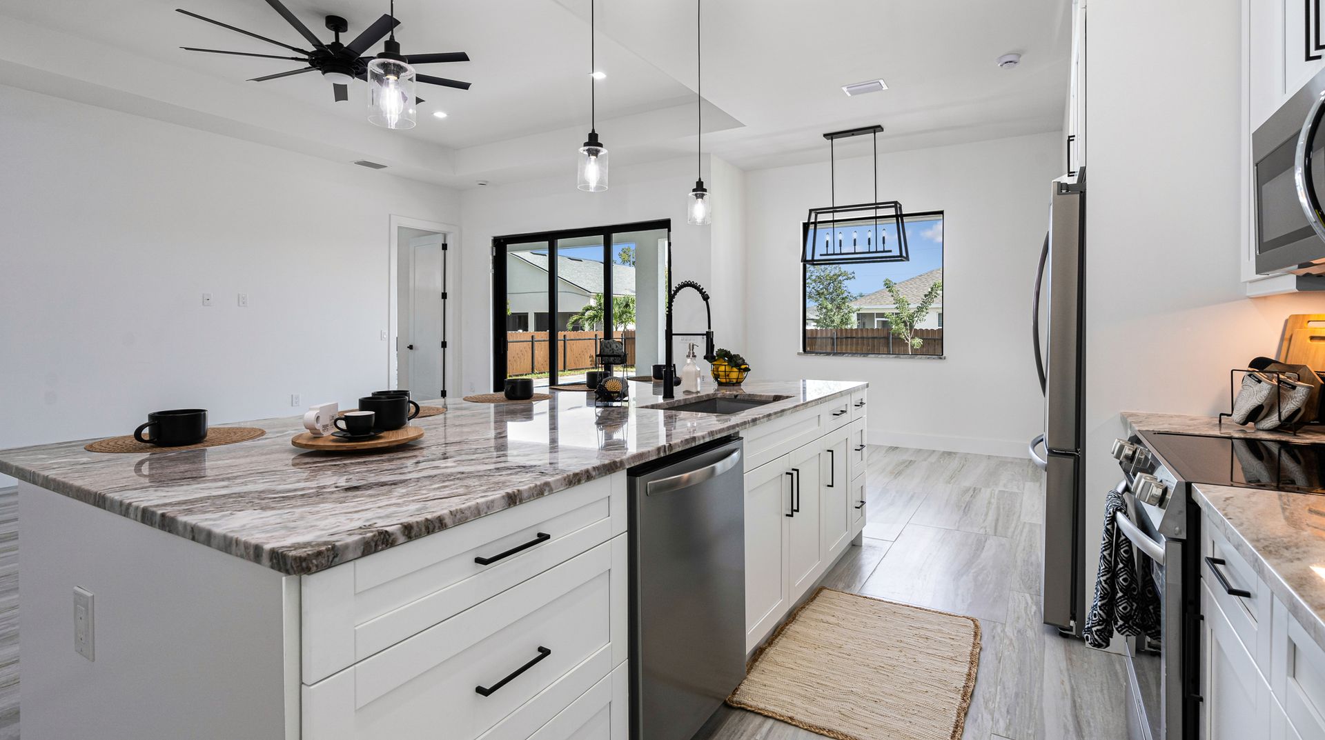 Modern kitchen with a large island, stainless steel appliances, and sliding glass doors.