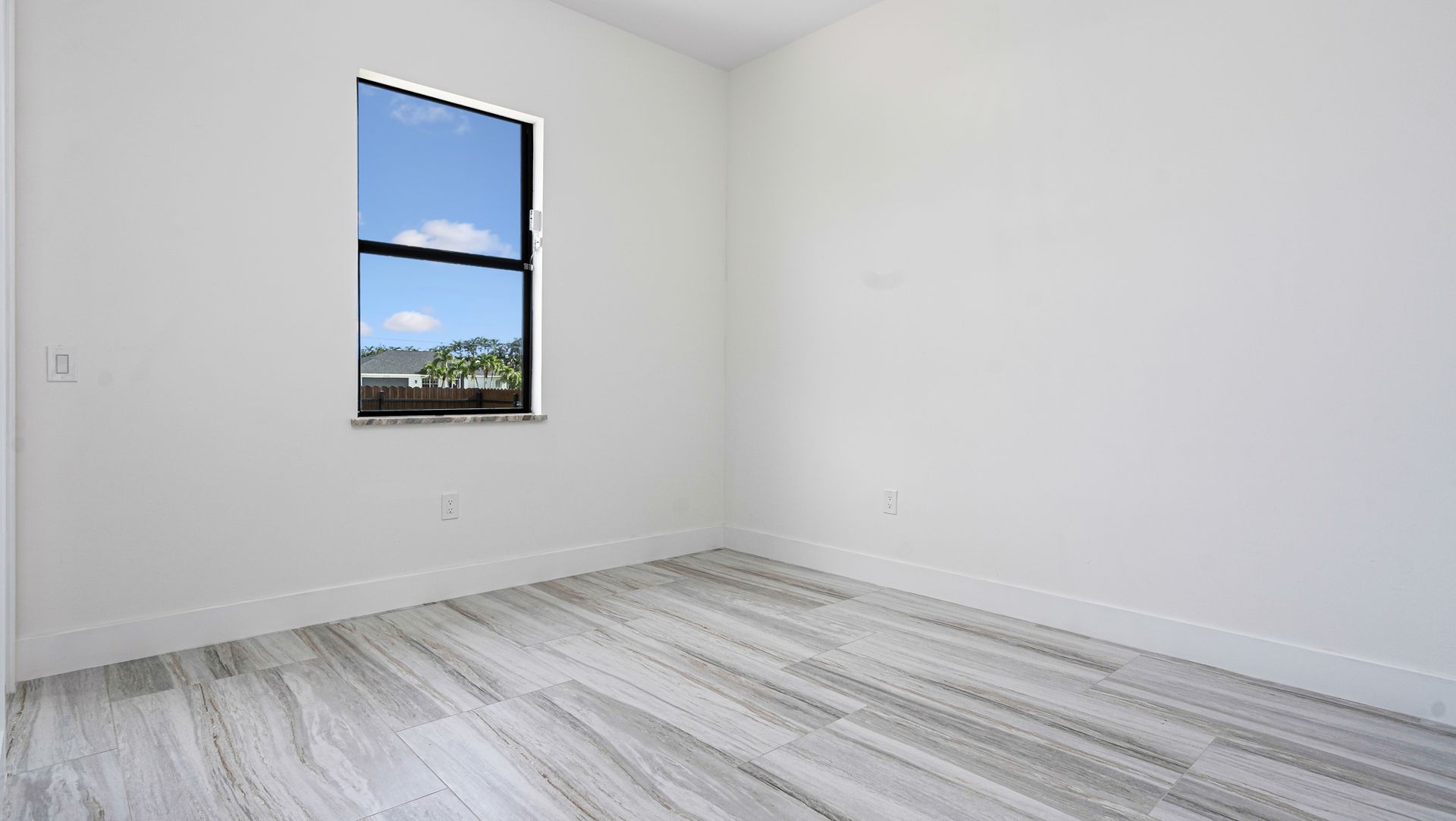 Empty room with white walls, window, and gray wood-look flooring.