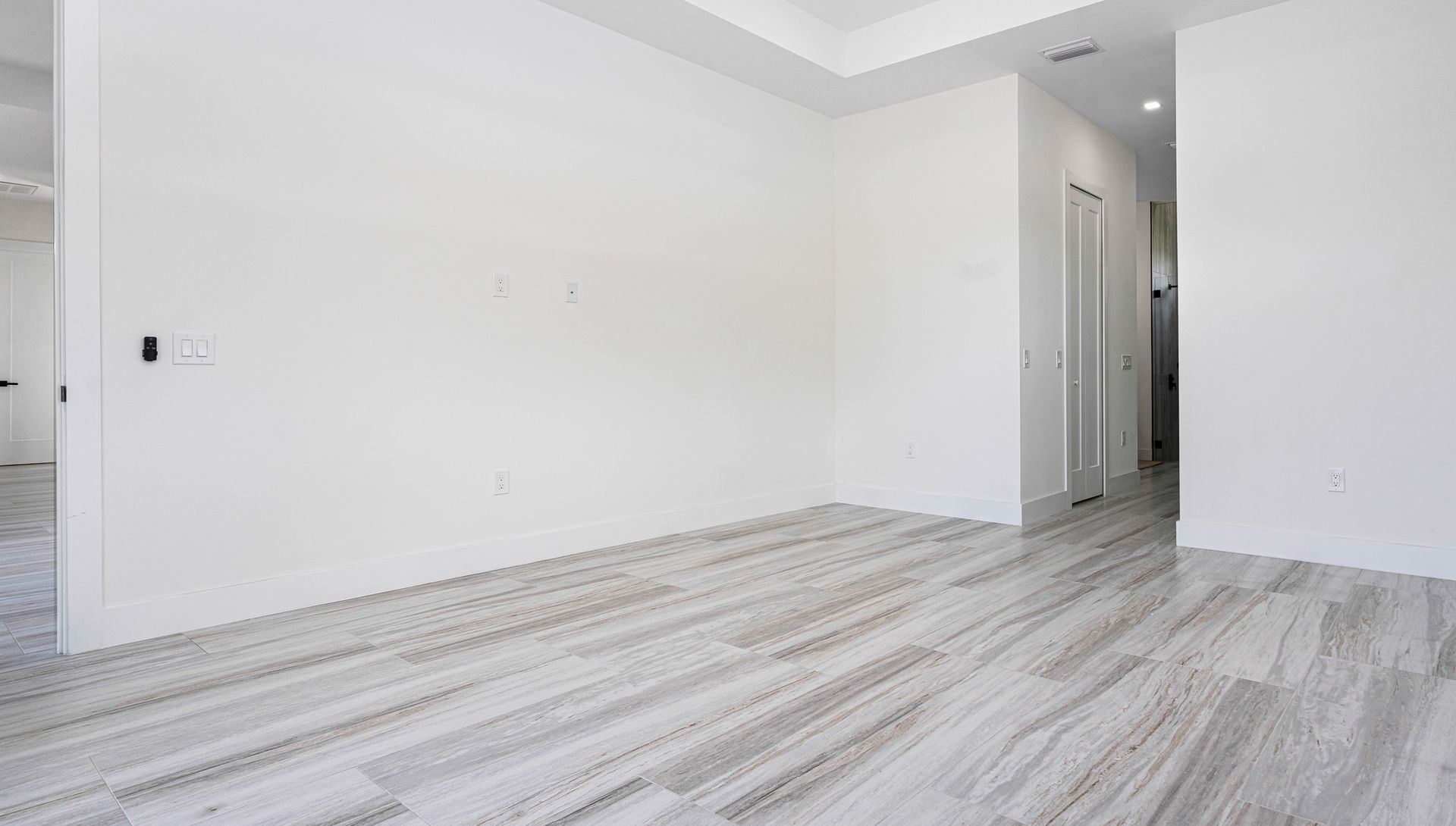 Empty room with light gray wood-look flooring, white walls, and doorways.