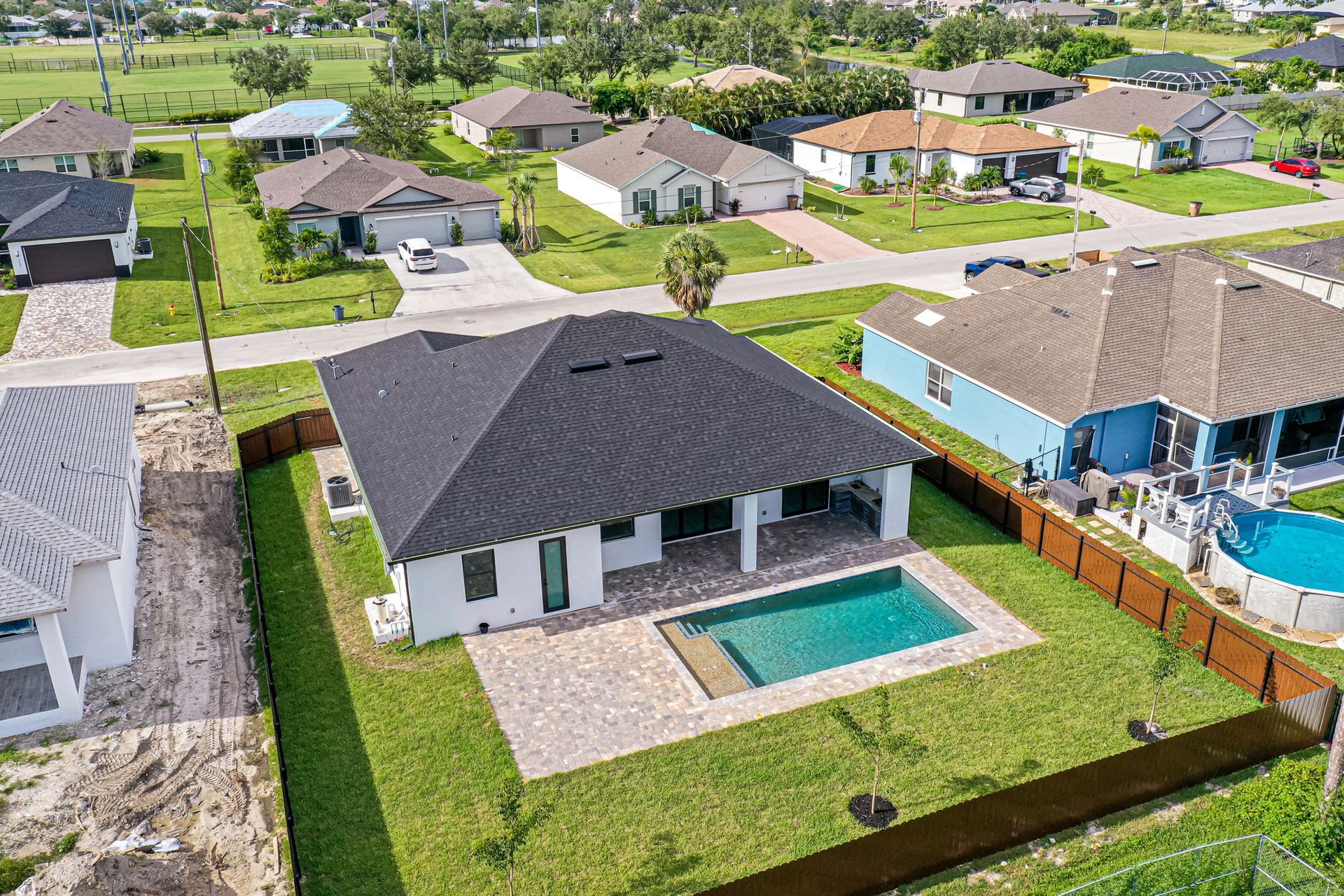Aerial view of a house with a pool in a suburban neighborhood.