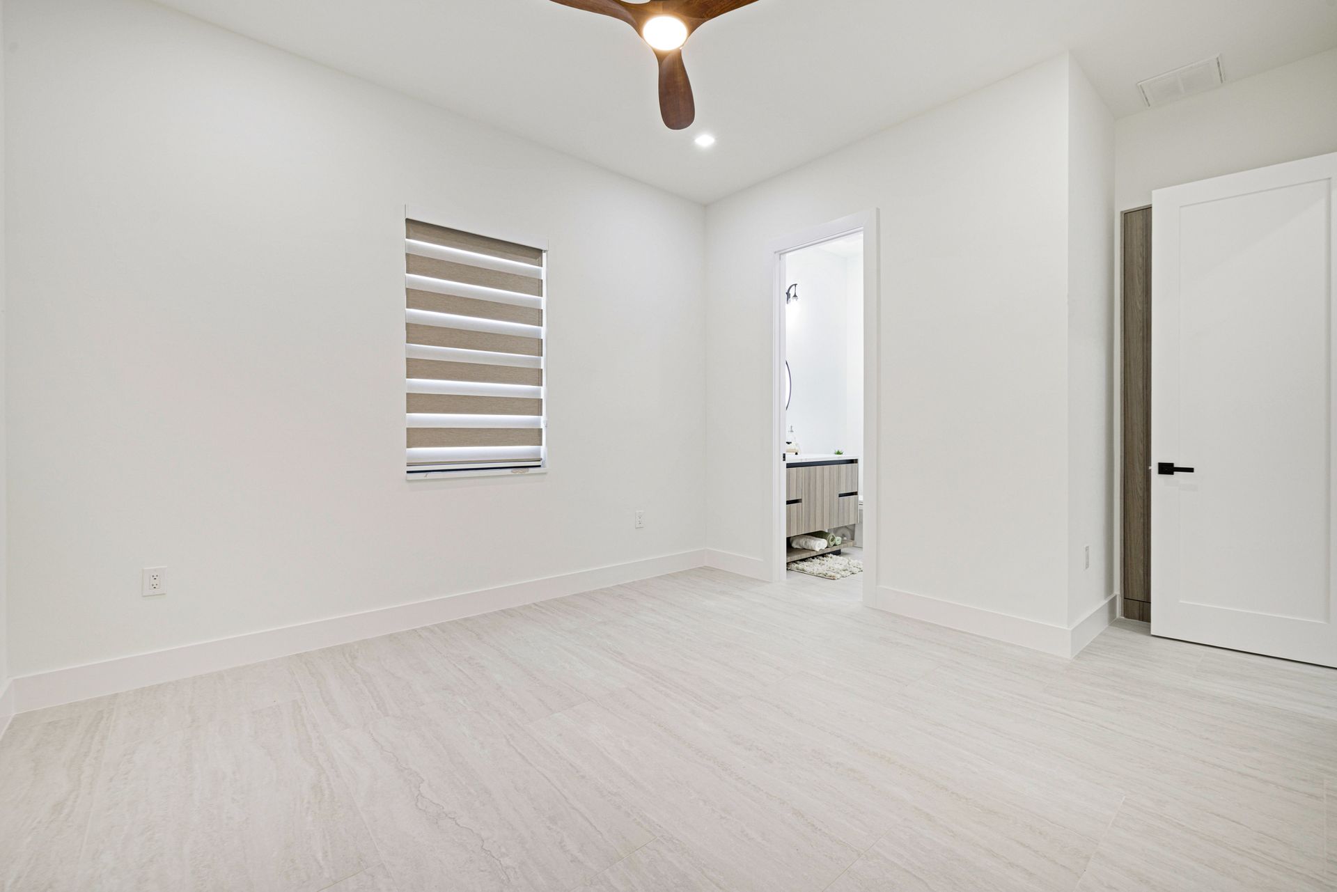 Empty white room with a window and a door, neutral colors, bright.