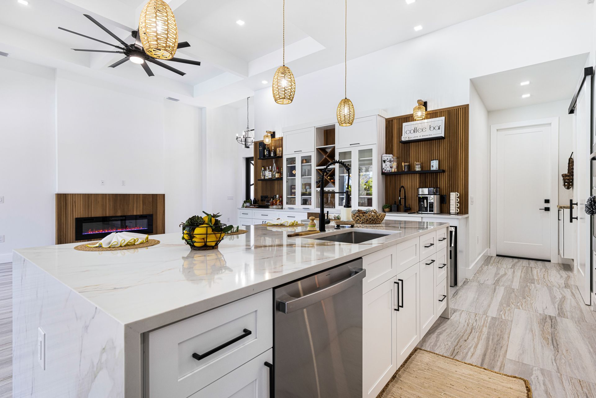 Modern kitchen with white cabinets, marble island, and wood accent wall.