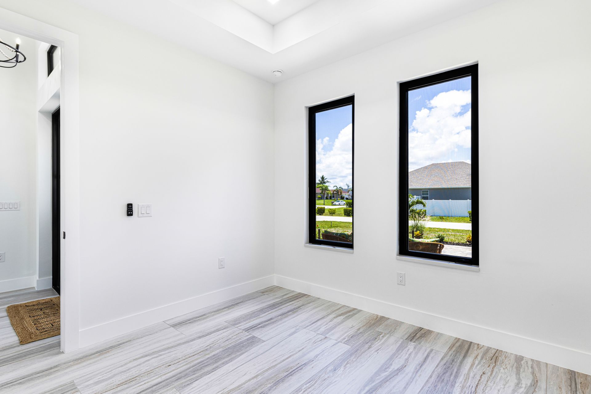 Empty room with white walls, two tall windows, and light wood-look flooring.