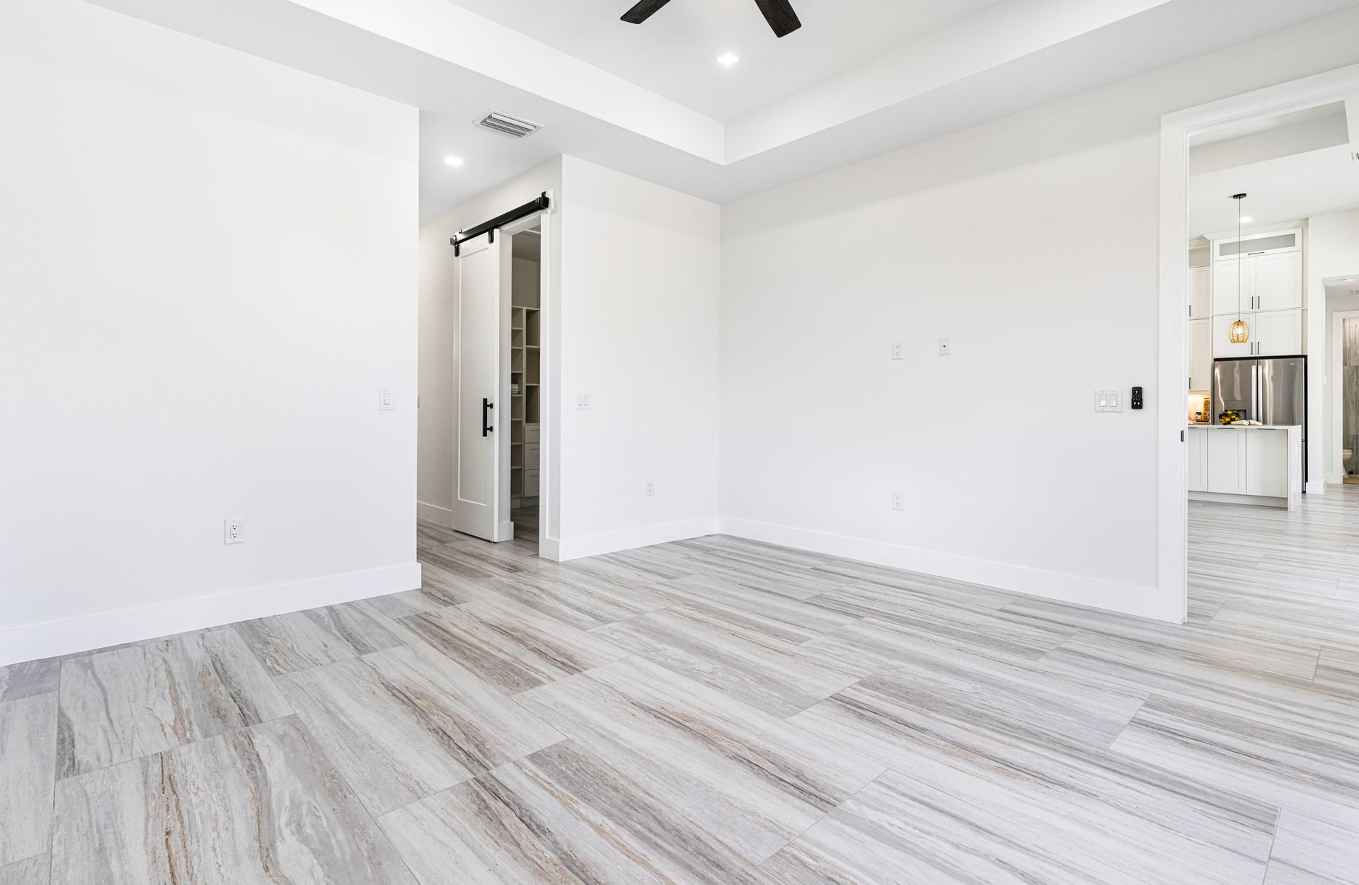 Empty room with light wood-look floor, white walls, and a sliding door to a bathroom.