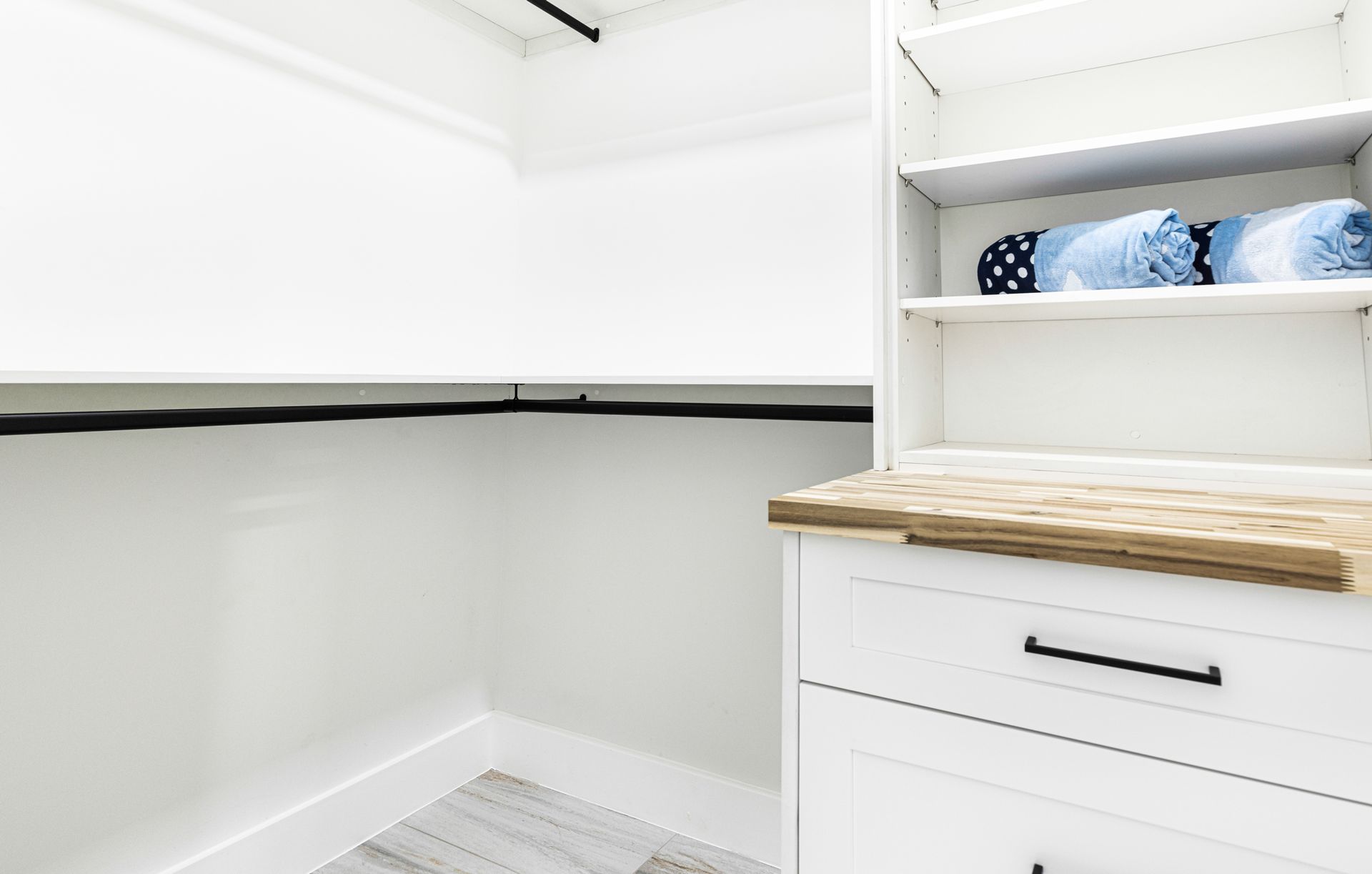 White closet with shelves, drawers, and rolled blue towels.