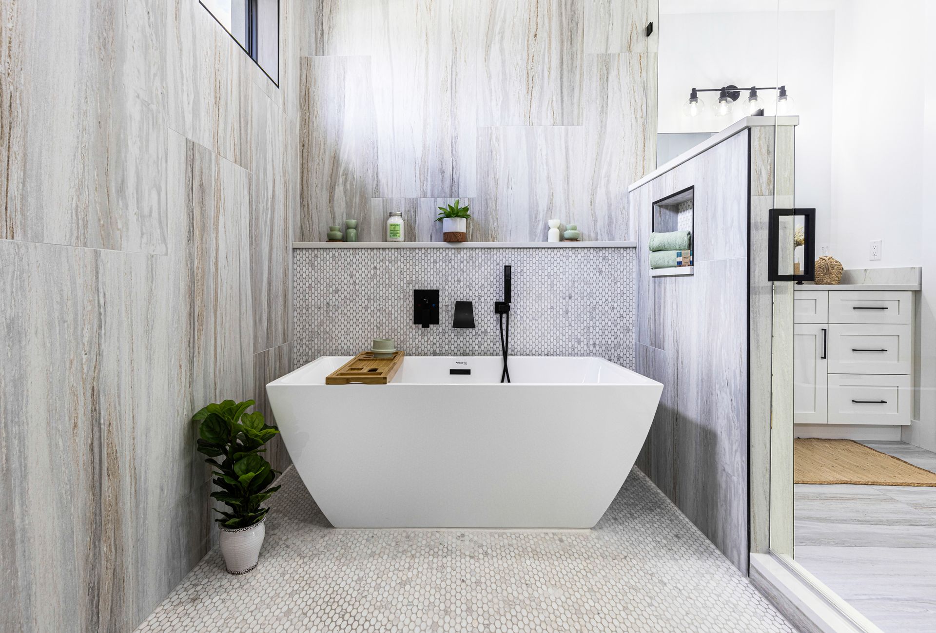 Modern bathroom with white tub, textured tile walls, and a rug.