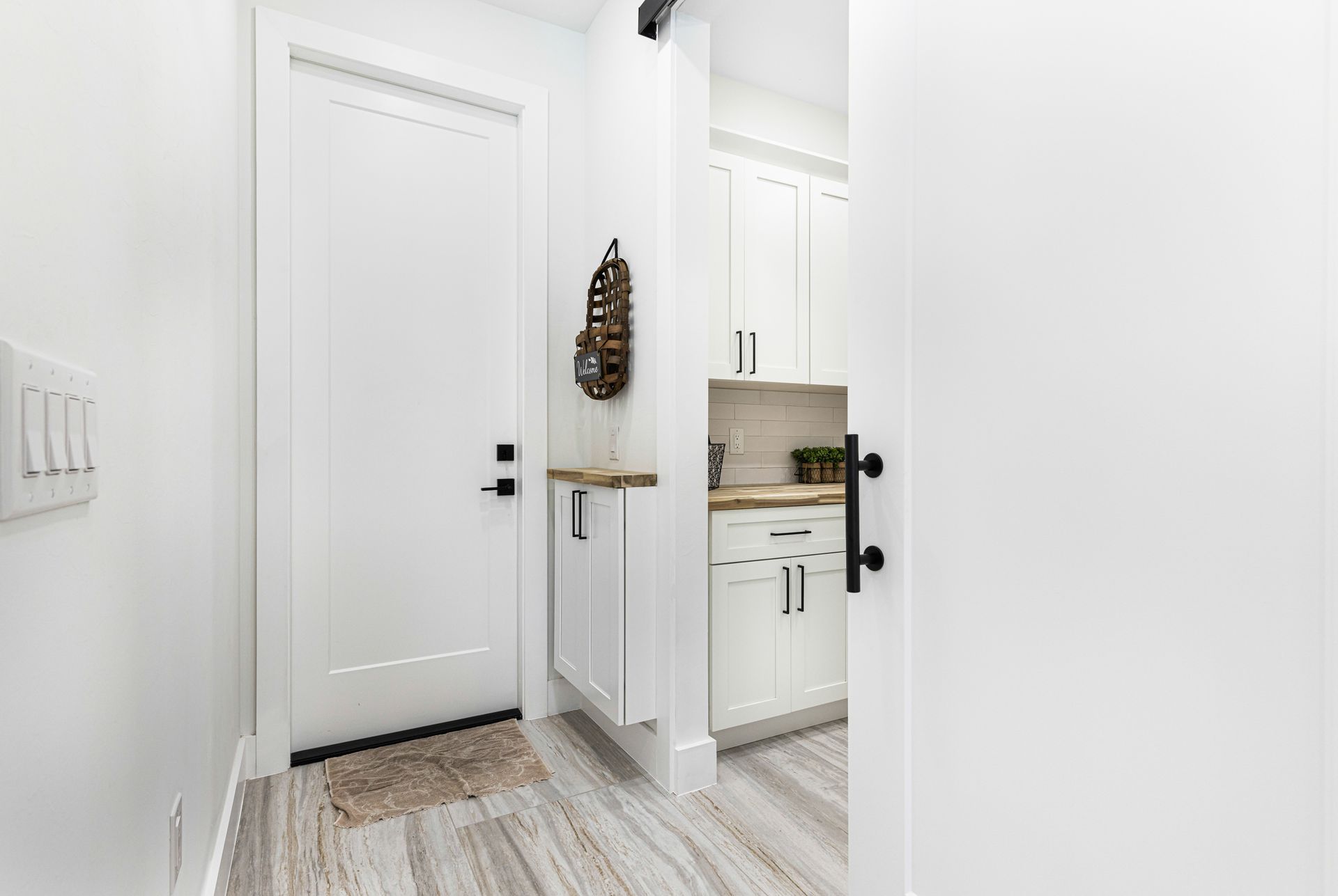 White hallway with white cabinets, door, and light switches.