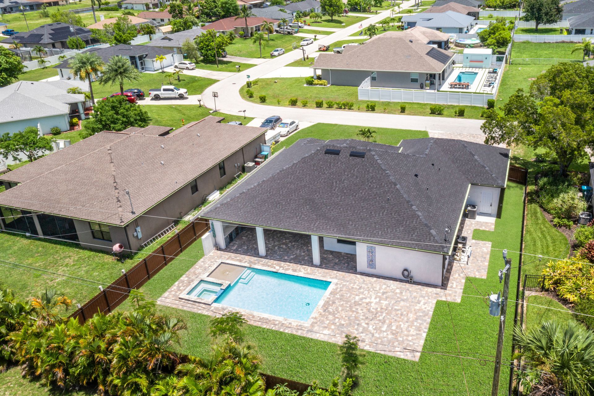 Aerial view of a house with a pool and patio in a residential neighborhood.