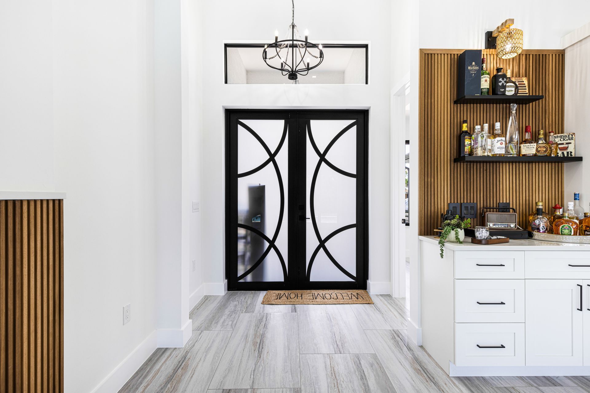 Entryway with black doors, white walls, wooden accents, and a bar area.