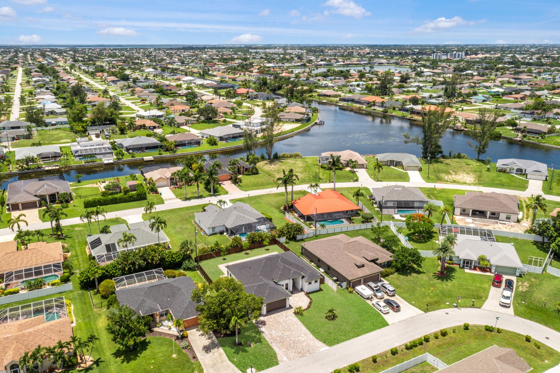 Aerial view of houses in a suburban neighborhood with canals and lush green lawns.