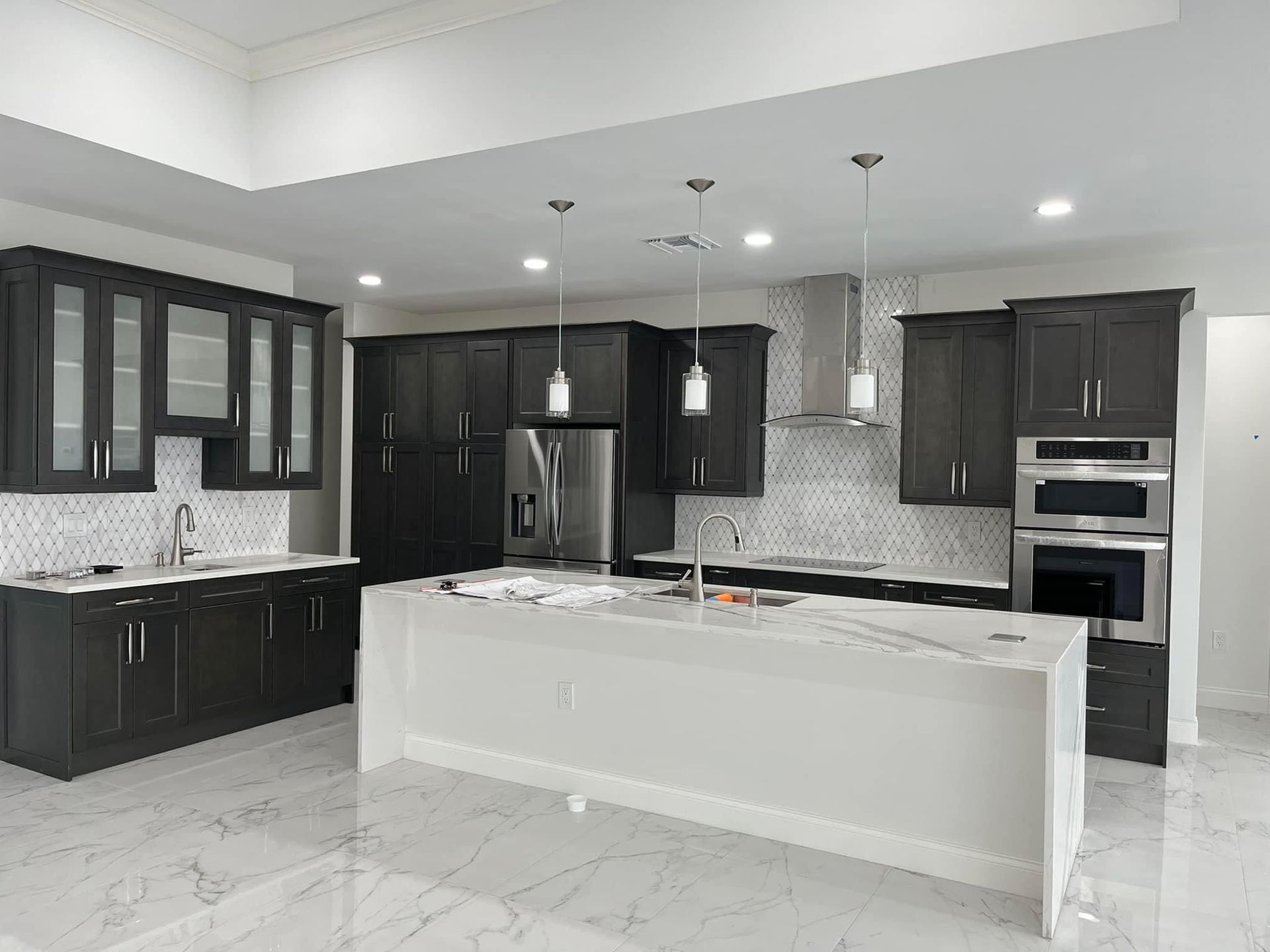 Dark gray kitchen cabinets, white countertops, stainless steel appliances, and a large island.