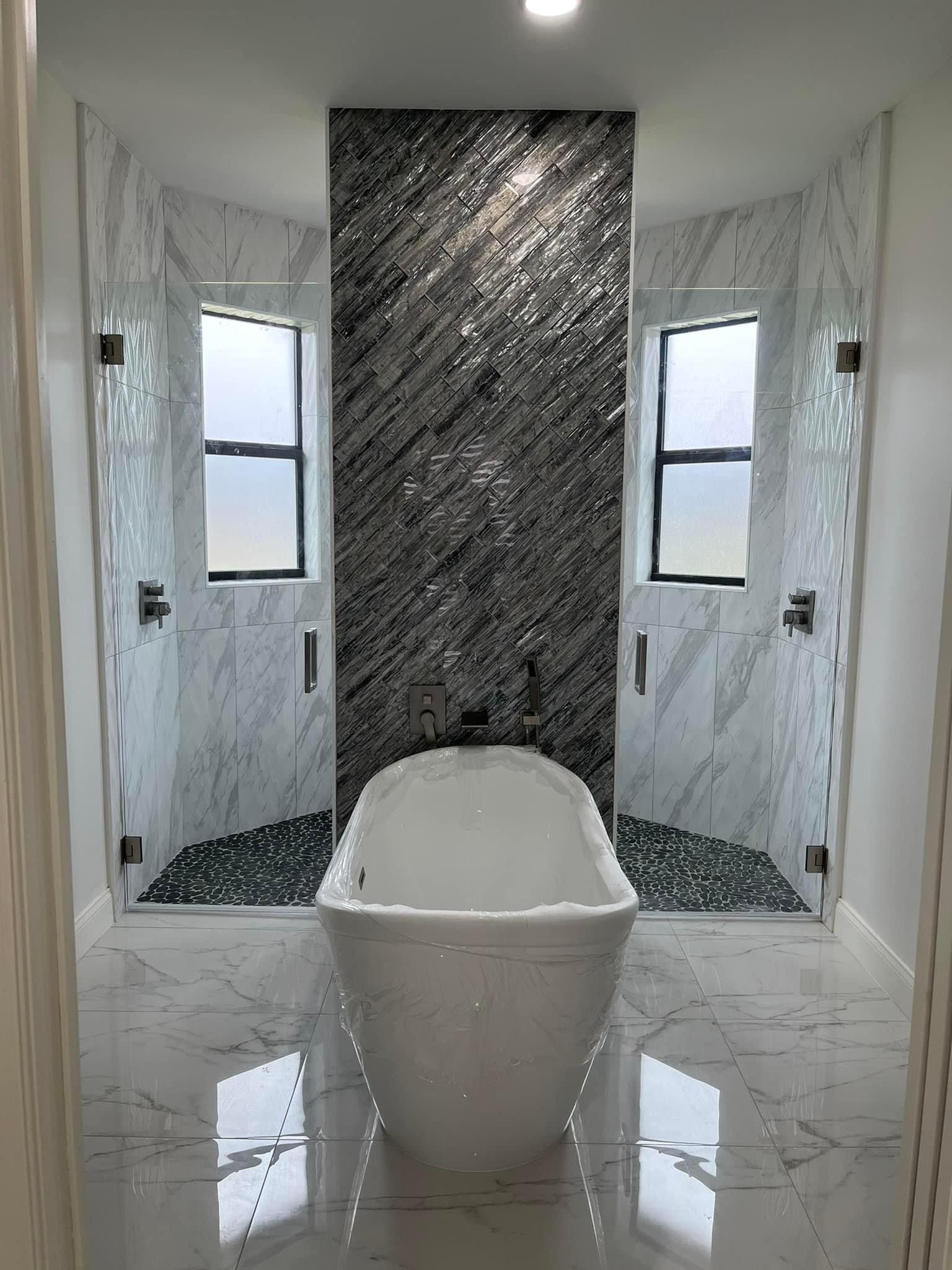 Modern bathroom with freestanding tub, two showers, and a gray mosaic accent wall.