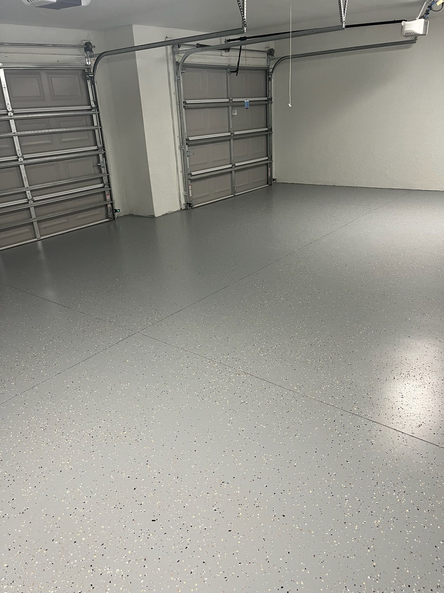 Gray epoxy-coated garage floor with two open garage doors.