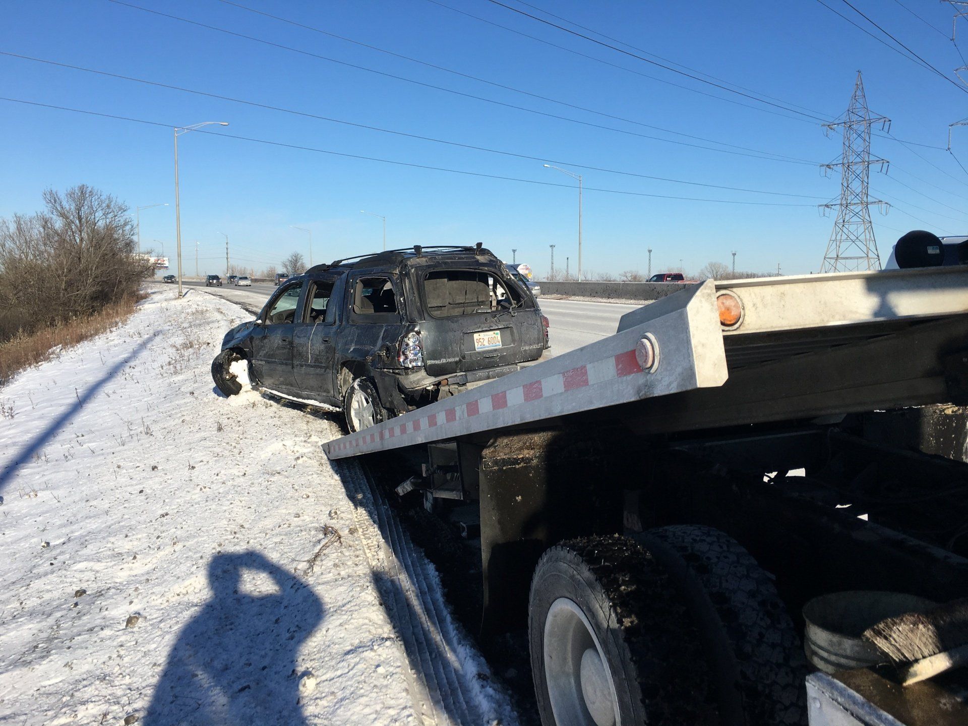 A car is being towed by a tow truck in the snow.