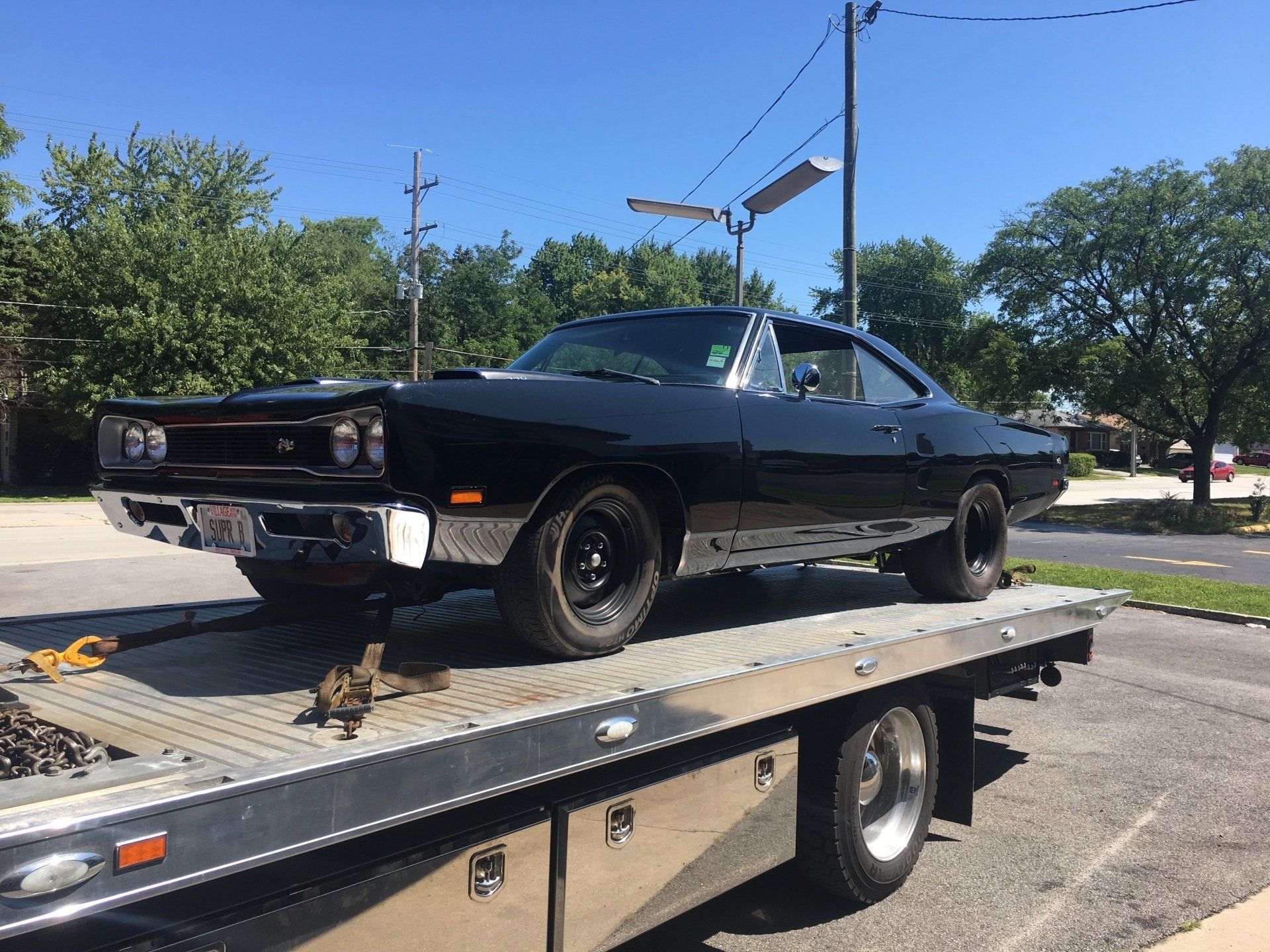 A black car is sitting on top of a tow truck.