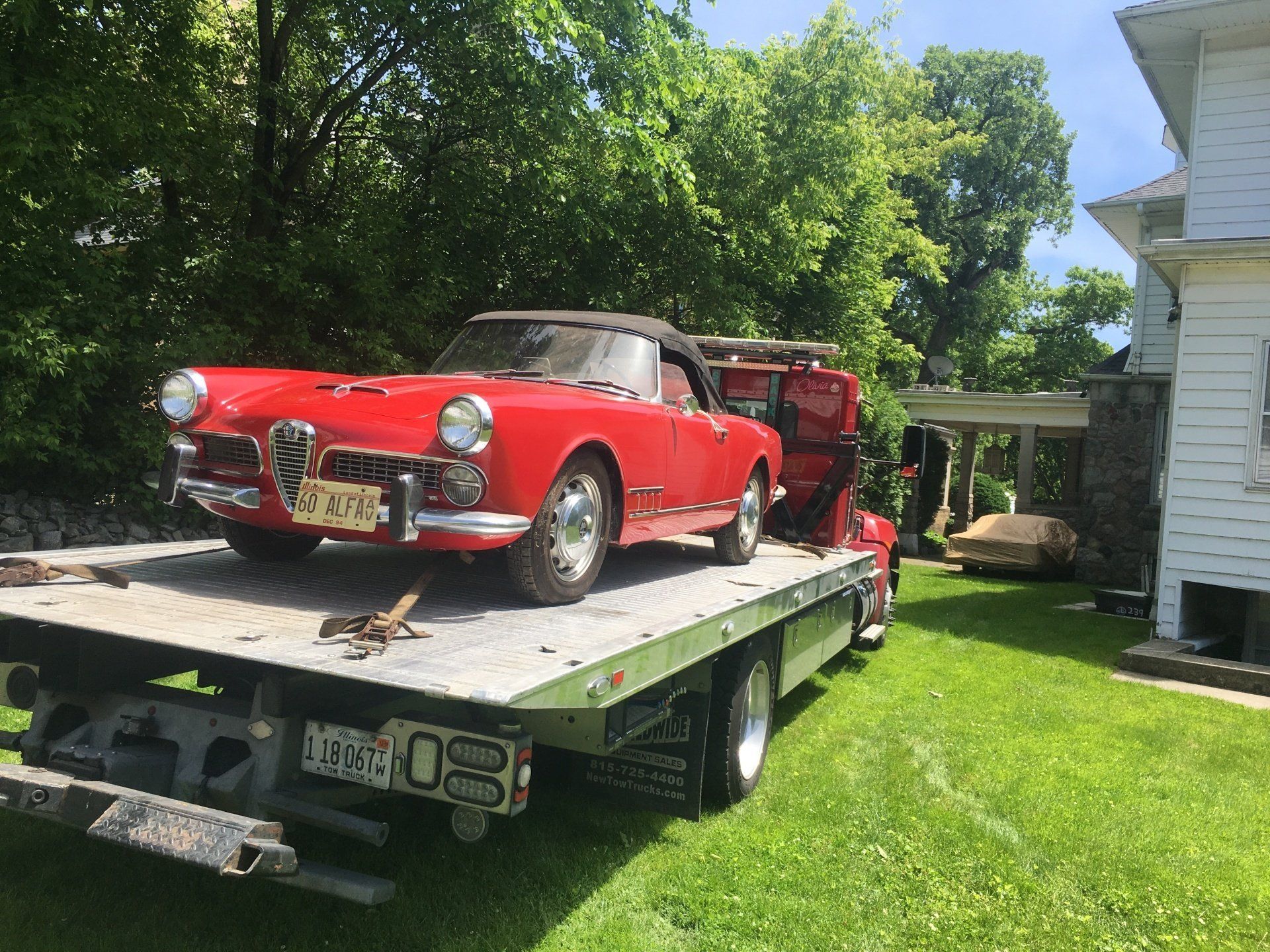 A red car is sitting on top of a tow truck.