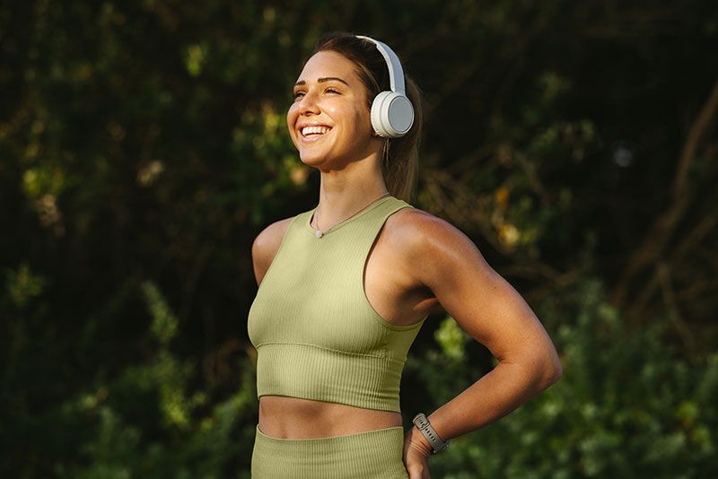 Women’s Wellness - Sports woman listening to a warmup playlist before a workout outdoors 
