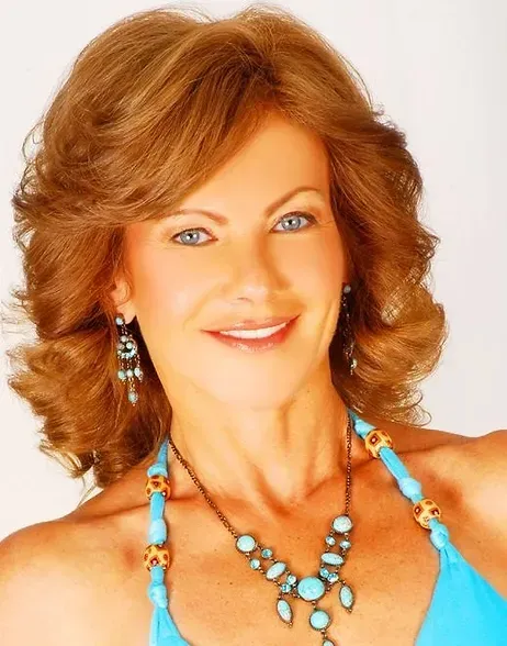 A woman wearing a necklace and earrings smiles for the camera