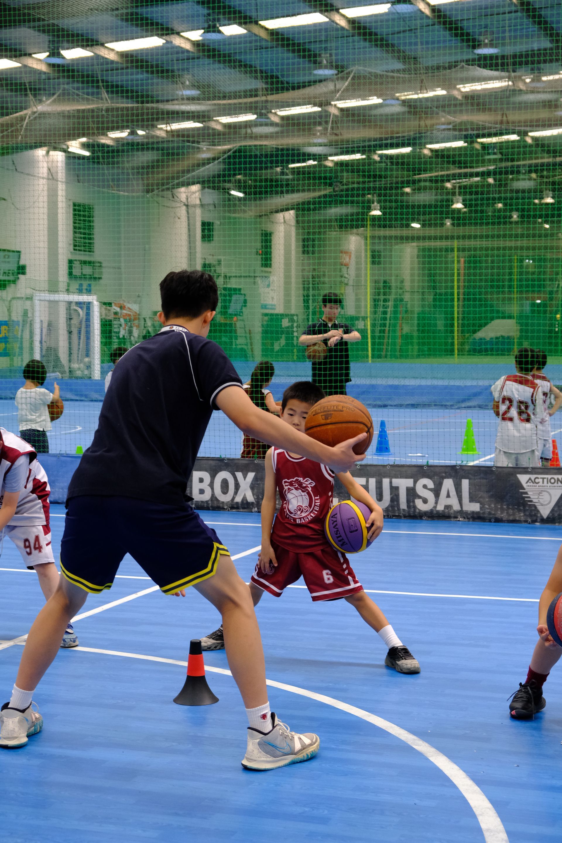 A group of children are playing basketball in a gym.