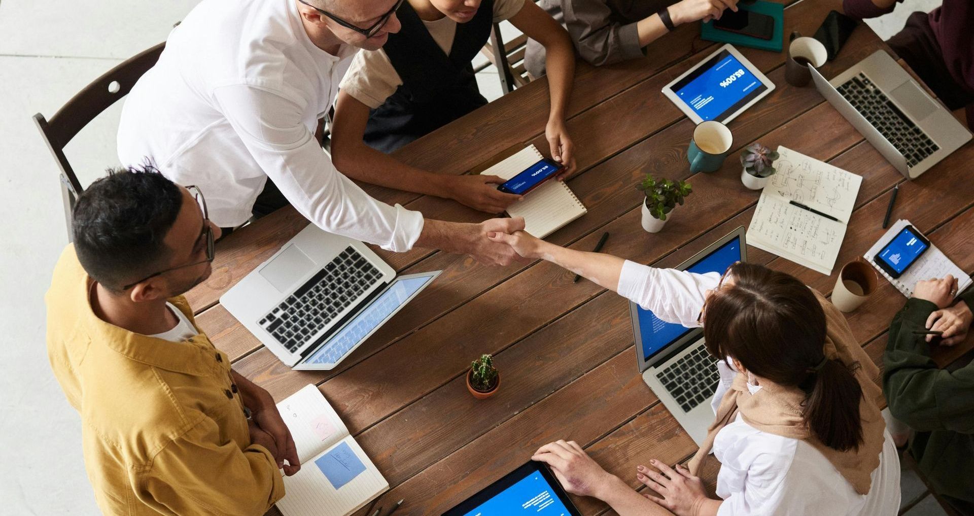 A group of people are sitting around a table shaking hands.