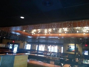 A restaurant with a ceiling that has christmas lights hanging from it
