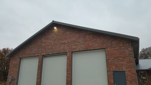 A large brick building with a black roof and white garage doors.