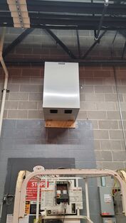 A stainless steel box is hanging from the ceiling of a building.