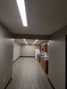 A long hallway leading to a kitchen with wooden cabinets and a refrigerator.