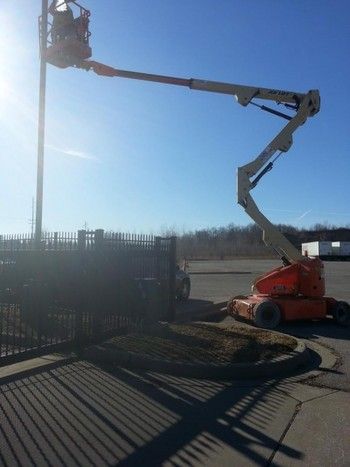 A man is working on a pole with a crane in a parking lot.