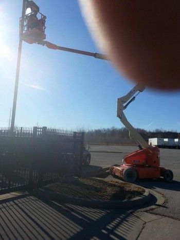 A man is sitting on a crane in a parking lot.