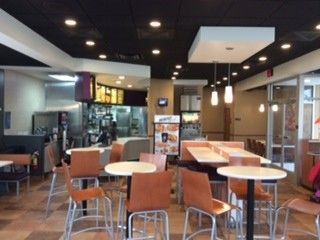 The inside of a fast food restaurant with tables and chairs