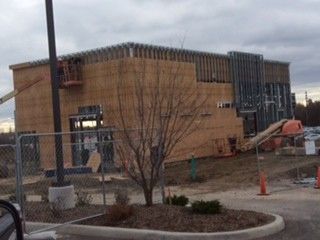 A building is being built in a parking lot with a fence around it.