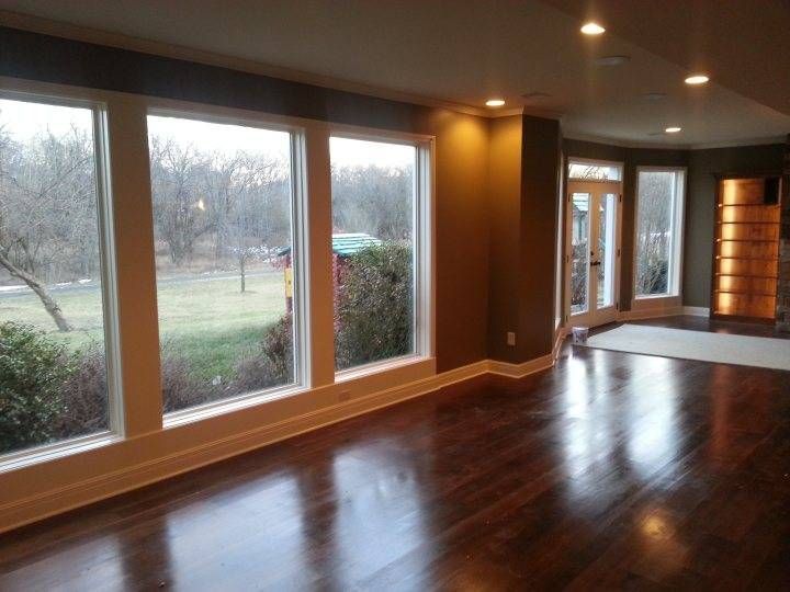 An empty living room with lots of windows and hardwood floors.
