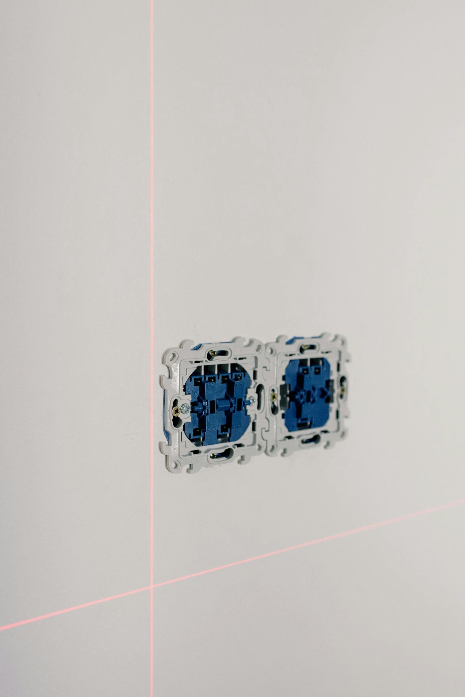 Two electrical outlets are being measured on a white wall.