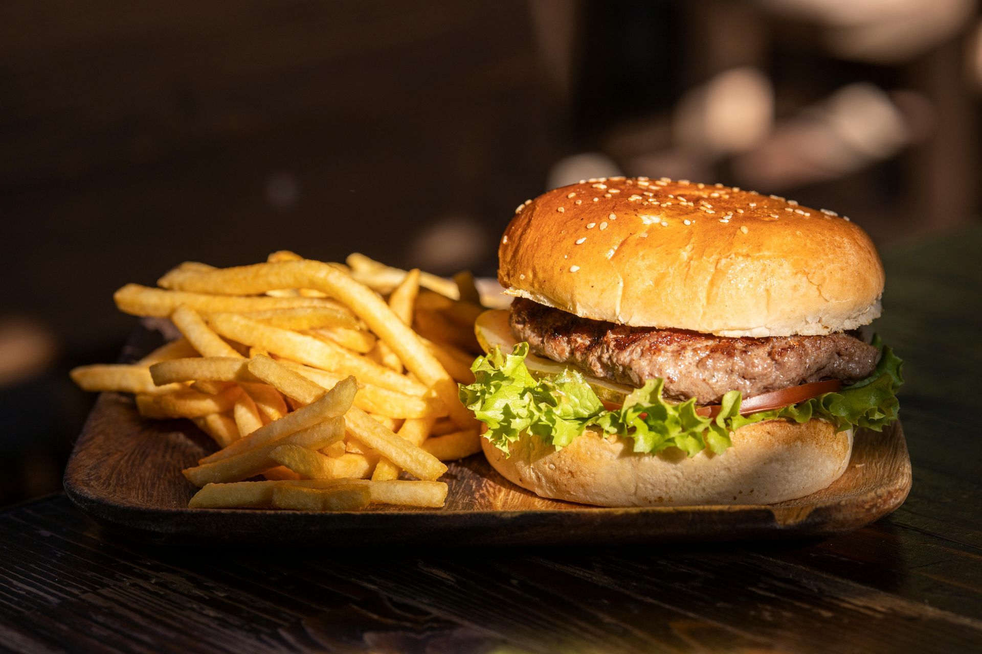 Burger and fries on plate on wooden table.