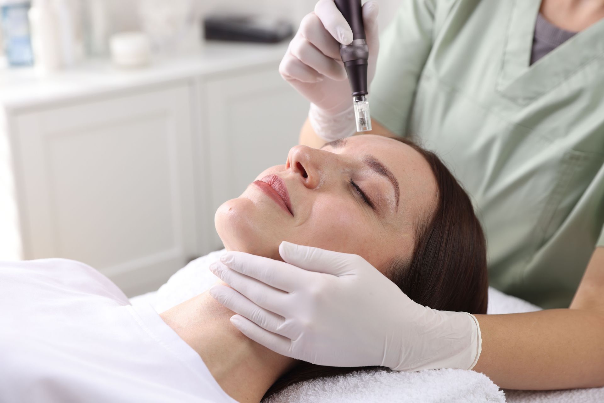 Cosmetic procedure on a woman’s face while wearing gloves in a bright clinic