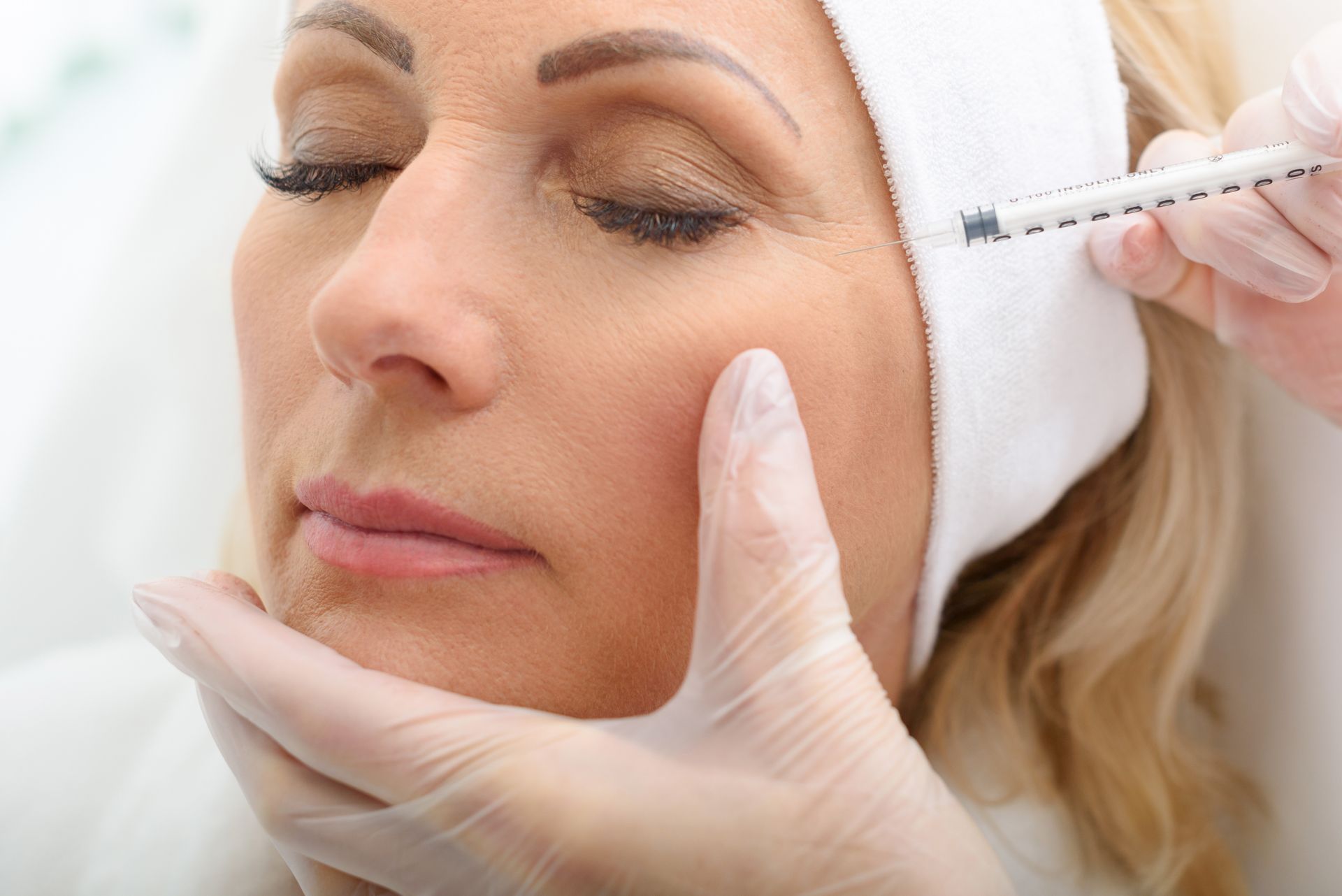 A woman is getting a botox injection in her face.