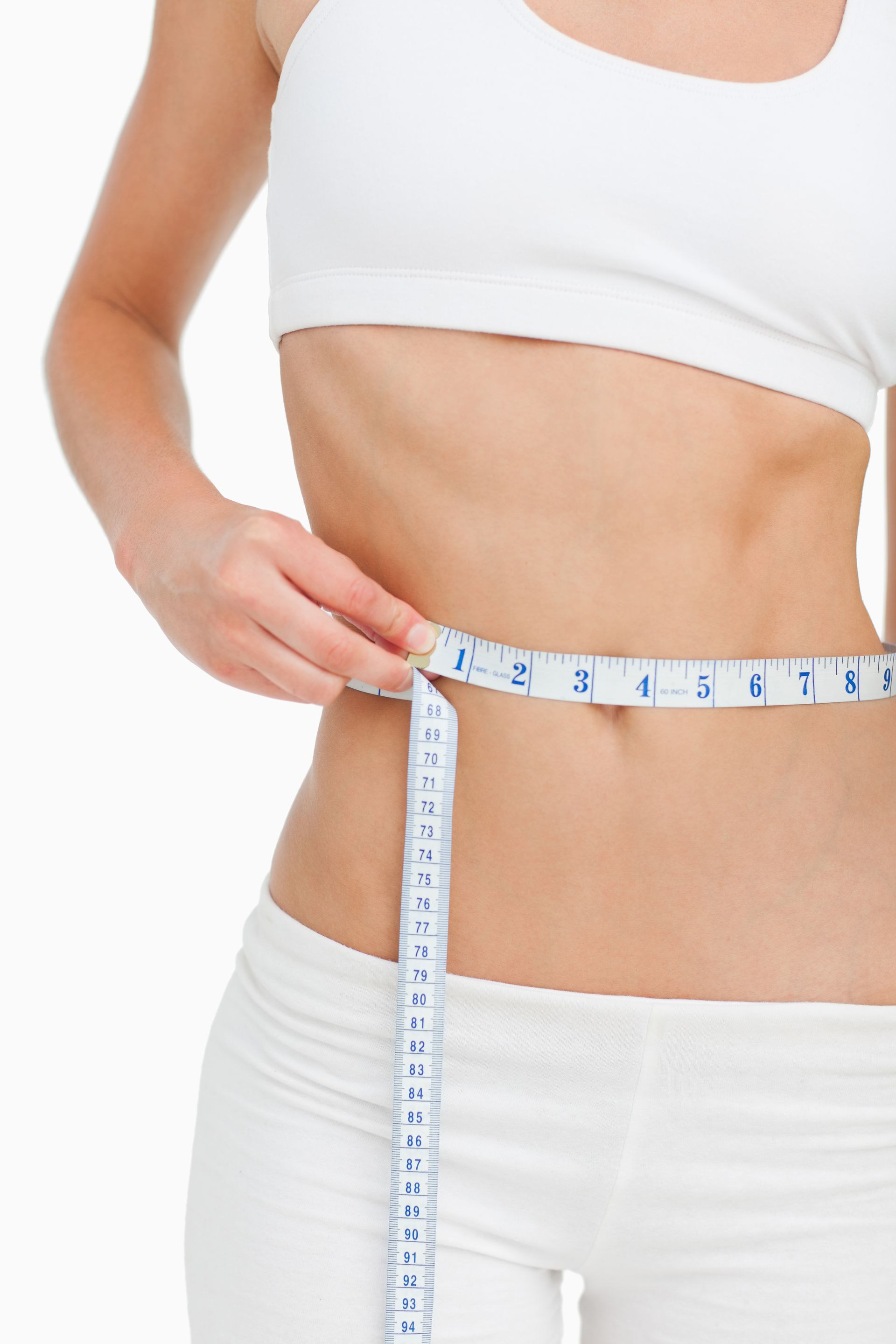 A woman is measuring her waist with a tape measure.