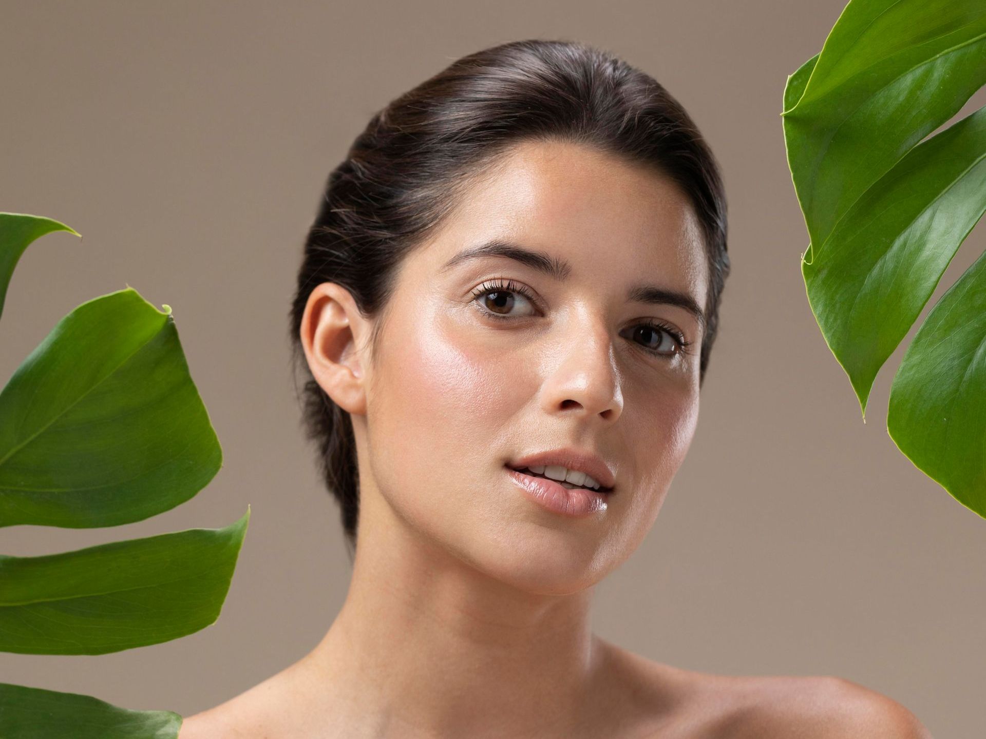 A close up of a woman 's face surrounded by green leaves.