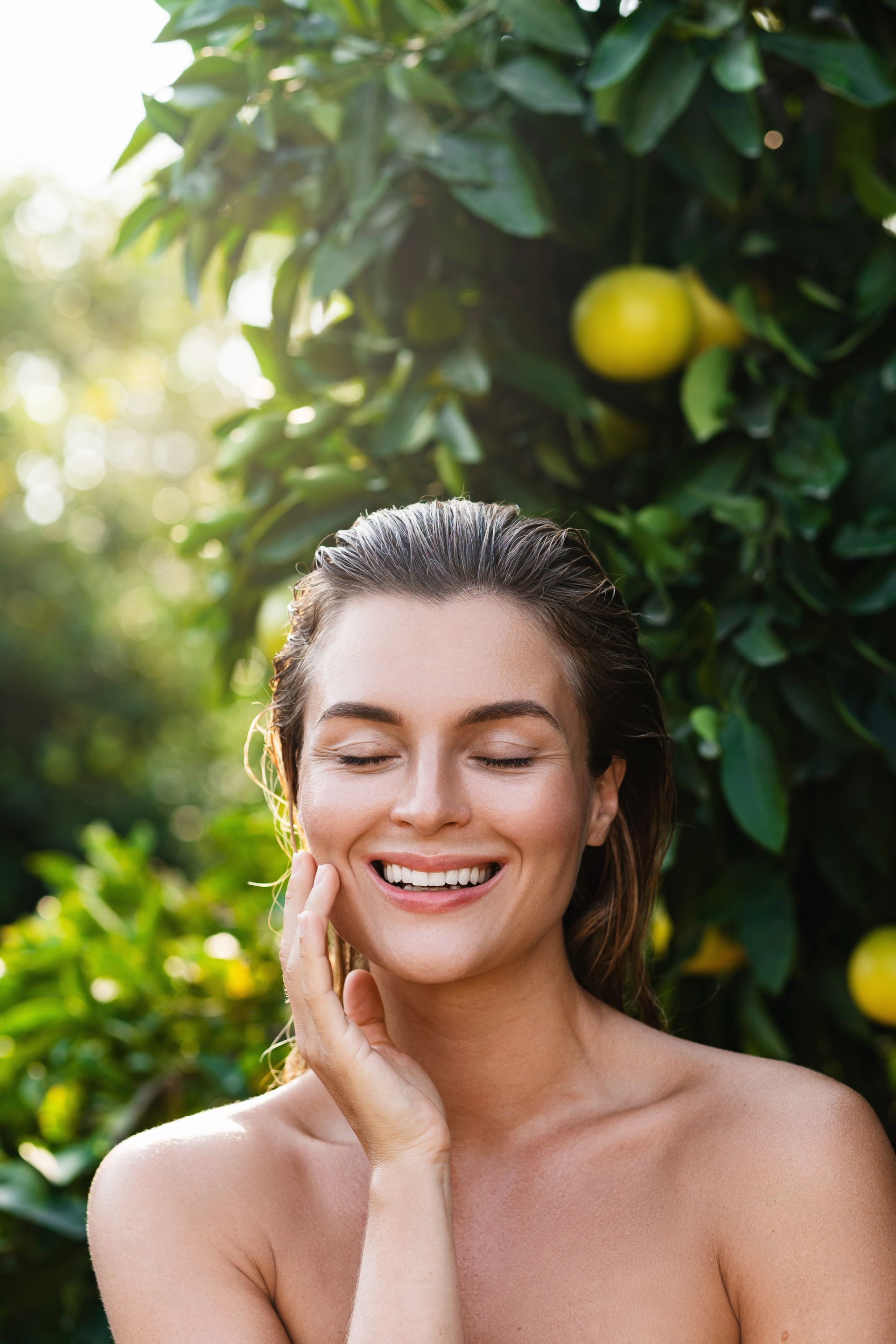 A woman is smiling and touching her neck with her hands.