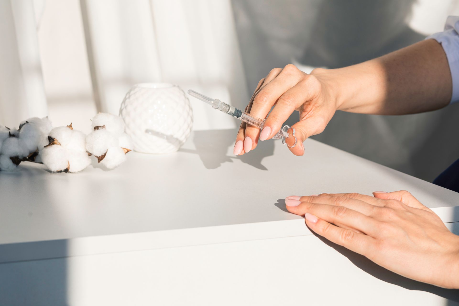 A woman is applying nail polish to her nails with a syringe.