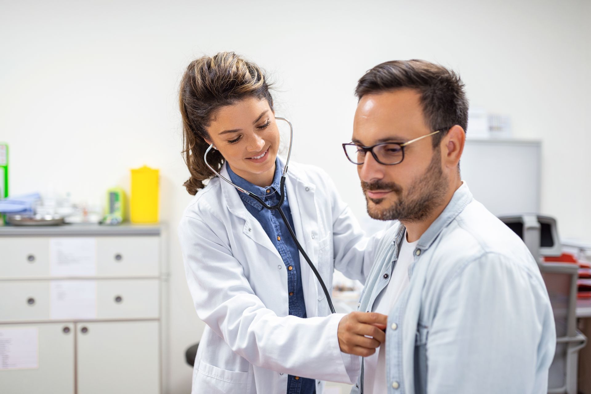 A doctor is listening to a patient 's heartbeat with a stethoscope.
