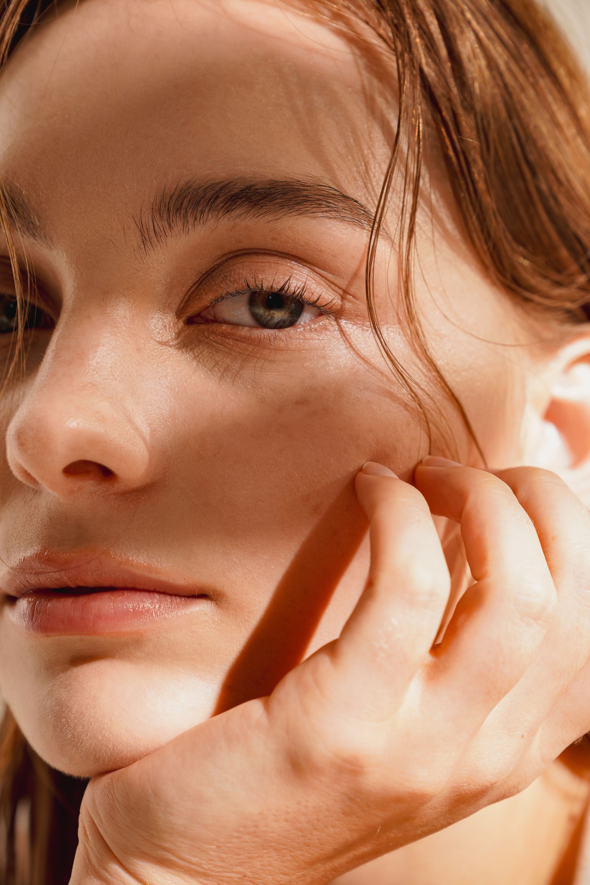 A close up of a woman 's face with her hand on her chin.