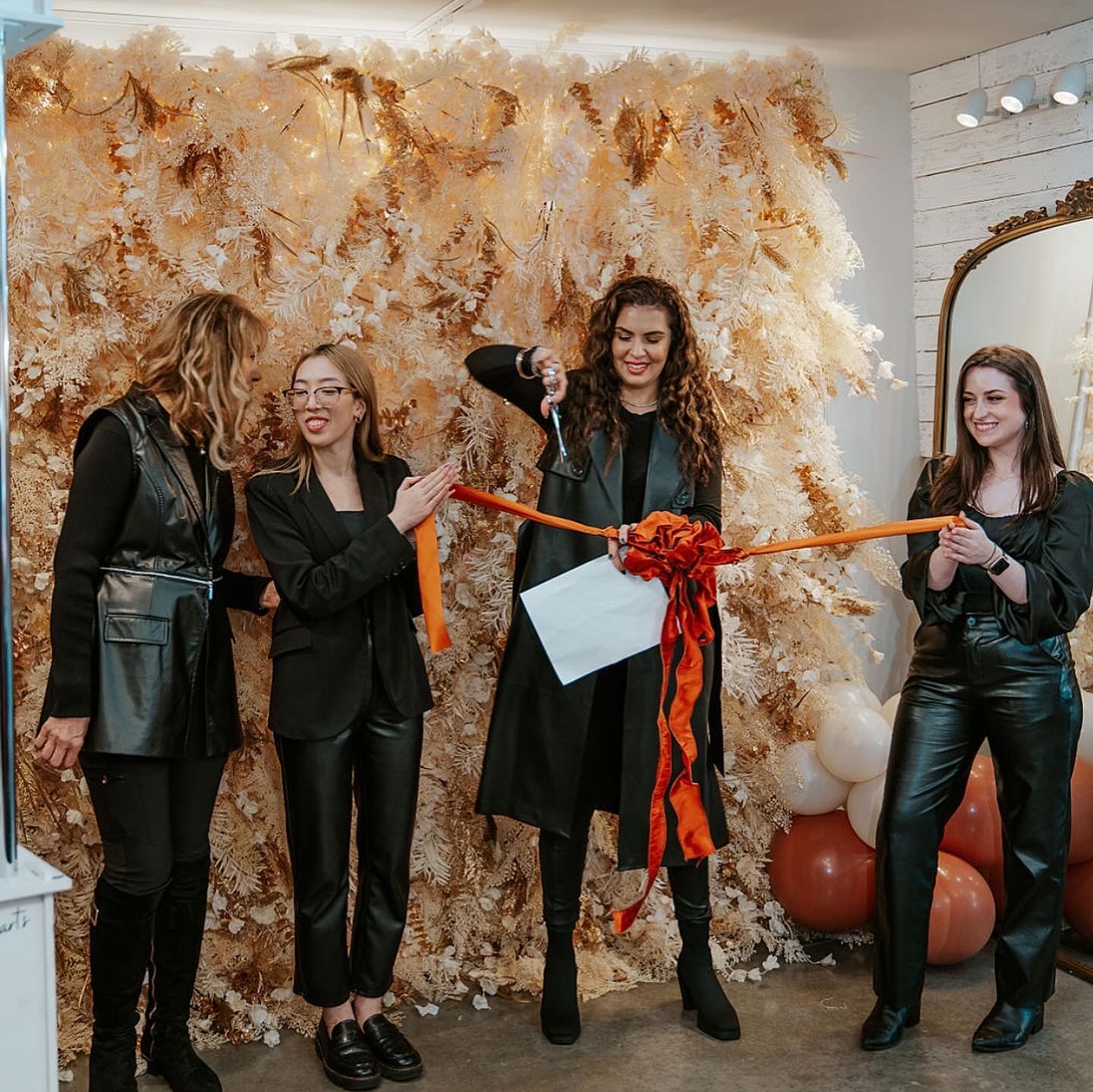 A group of women are standing next to each other cutting a ribbon.